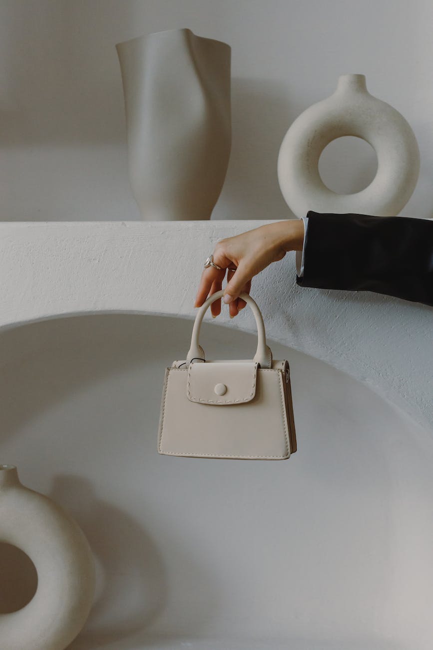 person holding beige leather handbag